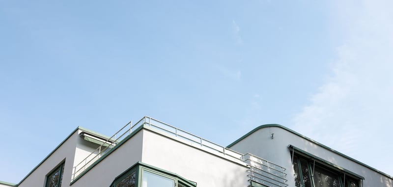 Vitt flerbostadshus mot blå himmel