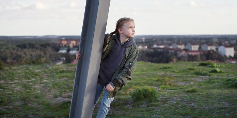 Flicka bakom järnstolpe spanar mot framtiden