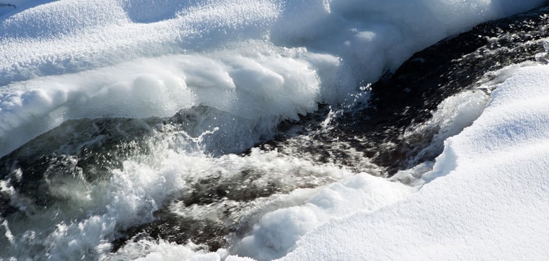 Forsande vatten kantat av snö